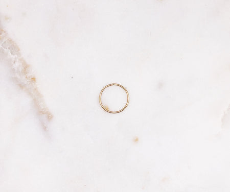 An organically formed fine gold ring displayed on a marble board.