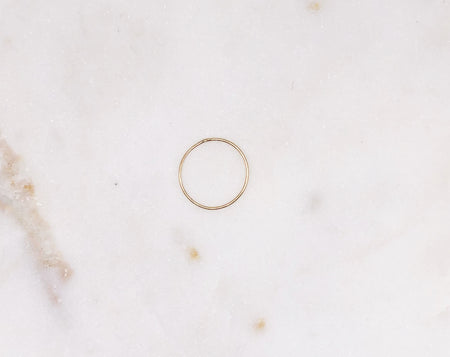 A delicate organically formed fine gold ring displayed on a marble board.