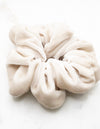 A luxurious pale pink silk scrunchie displayed on a marble board.