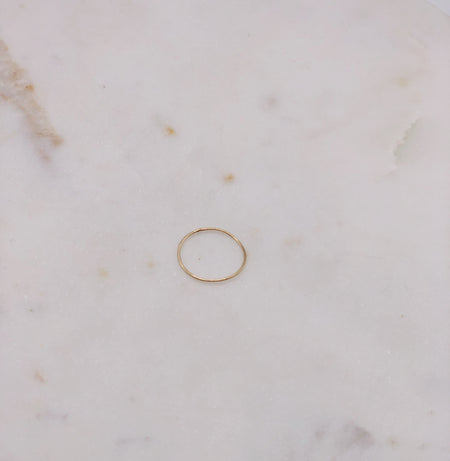 A delicate organically formed fine gold ring displayed on a marble board.