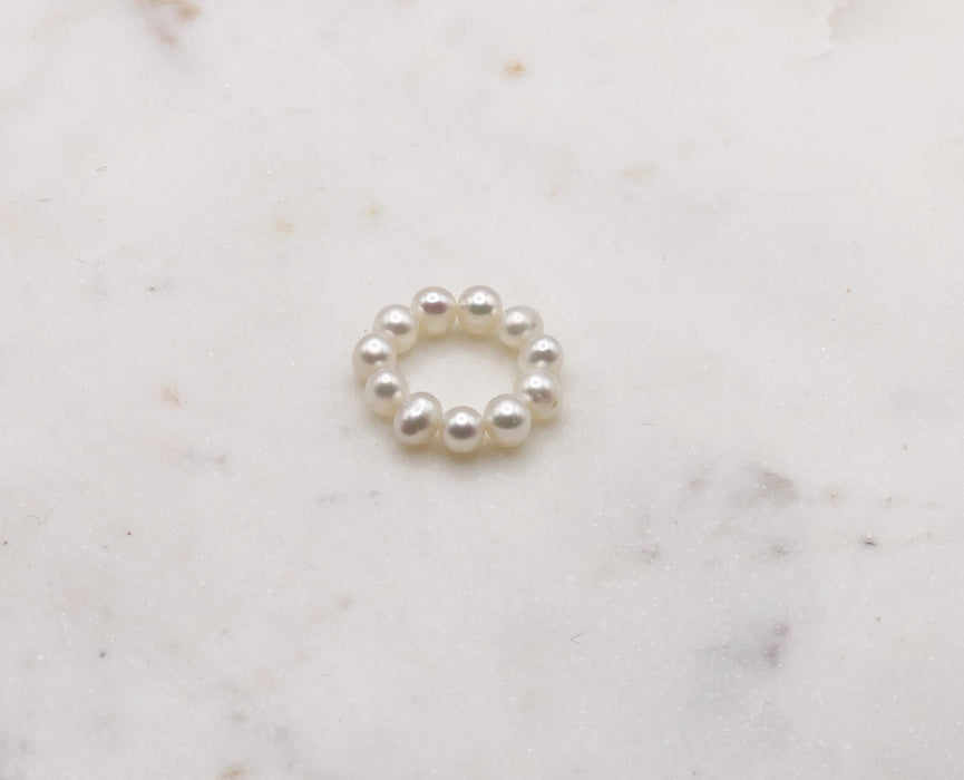 A white pearl ring made from Fresh Water Pearls displayed on a marble board.