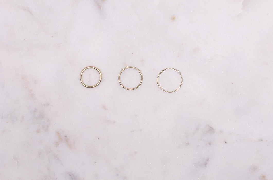 Three gold rings displayed on a marble board.