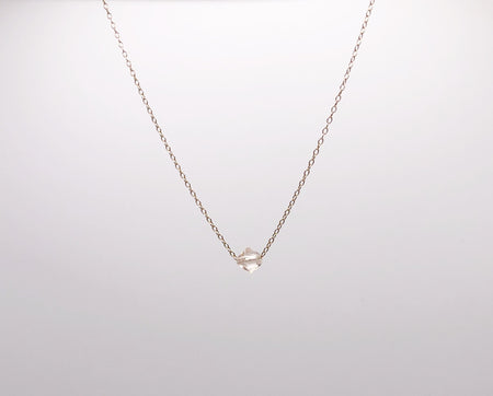 A single crystal hanging from a delicate gold chain necklace.