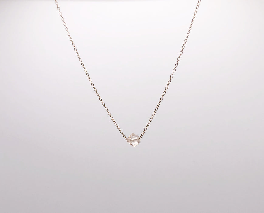 A single crystal hanging from a delicate gold chain necklace.