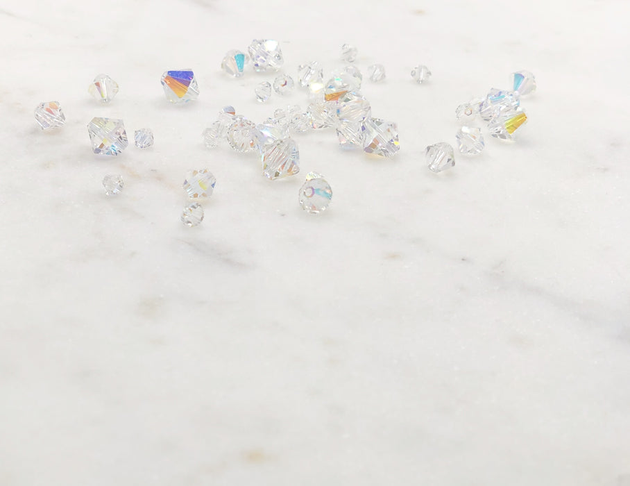 Rainbow Crystals of varying sizes scattered over a marble board.