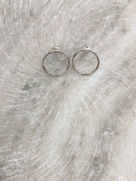 A close up photograph of a pair of silver hoop studs lightly textured displayed in a shallow marble bowl. The earrings measure approximately 2cm each in diameter.